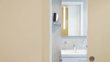 Un baño con un lavabo blanco, un espejo y un inodoro.