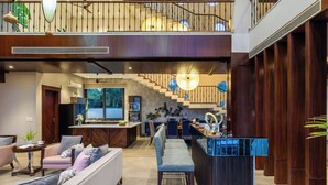 A modern interior with a staircase, a kitchen area, and a seating area with a sofa and chairs.