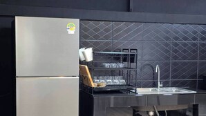 Une cuisine moderne dotée d’un réfrigérateur en acier inoxydable, d’un crédence en carreaux noirs et d’un évier avec un robinet.