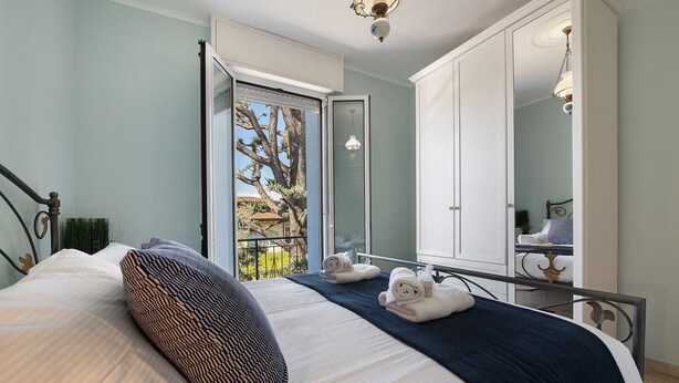 Quarto com cama, varanda, guarda-roupa e espelho.