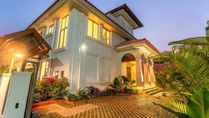 A two-story house with a tiled driveway and a well-maintained garden. - ELIVAAS Casa Bonita 4BHK Villa With Pool (Marra)