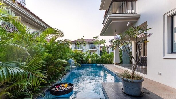 A swimming pool with a hot tub, surrounded by lush greenery and a potted plant. - ELIVAAS Casa Bonita 4BHK Villa With Pool (Marra)