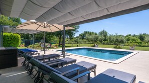 A covered outdoor area with a swimming pool, lounge chairs, and umbrellas. - Hacienda Afrodita by Villas Guide (Loborika)