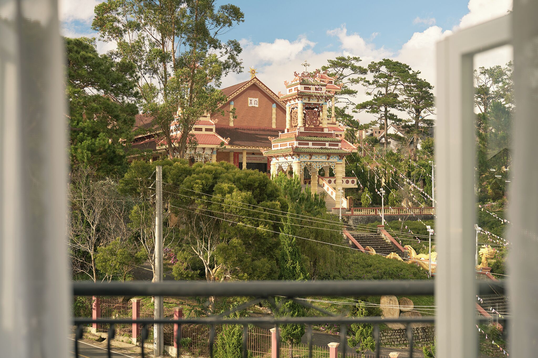 A large, ornate building with a prominent tower and multiple levels, surrounded by lush greenery.
