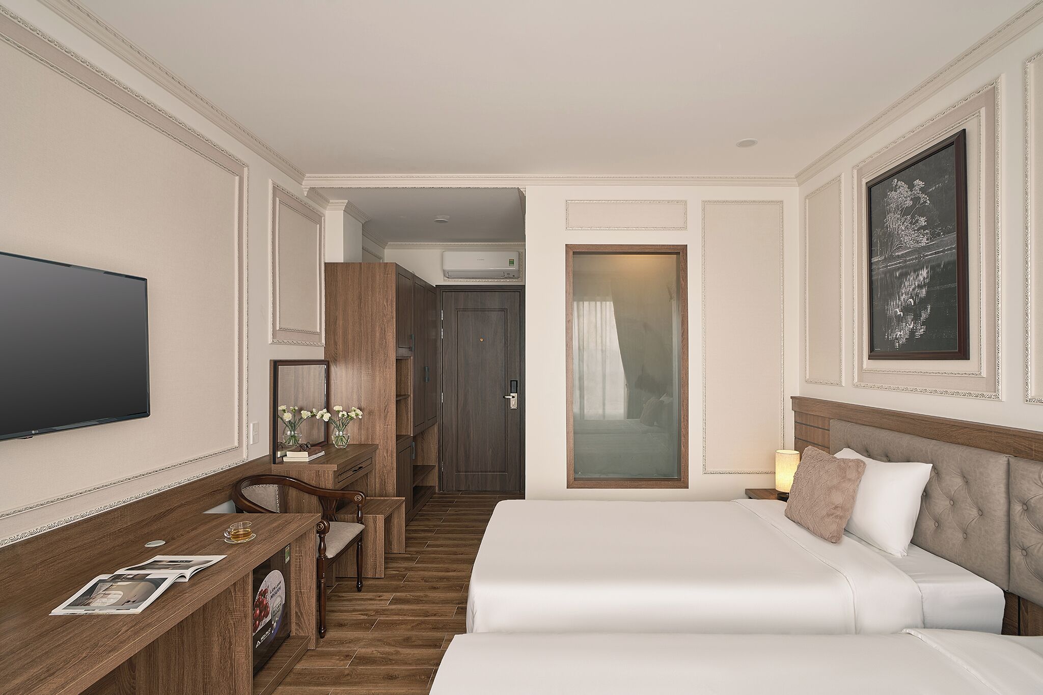 A hotel room with a bed, a desk with a chair, a TV, and a framed picture on the wall.