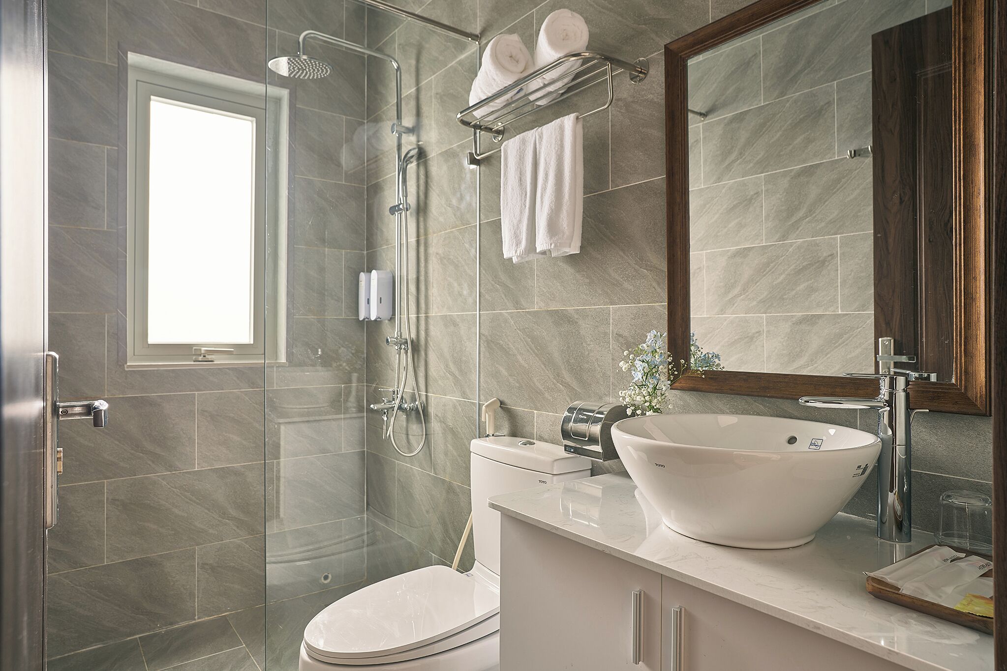 A modern bathroom with a glass-enclosed shower, a white sink, and a toilet.