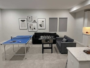 Una sala de estar con una mesa de fútbol de mesa, una mesa de ping pong y un sofá.