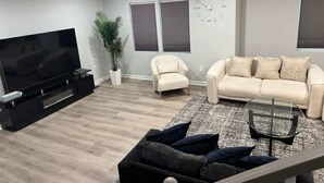 Ett modernt vardagsrum med en platt-TV, en soffa, en fåtölj och ett soffbord.