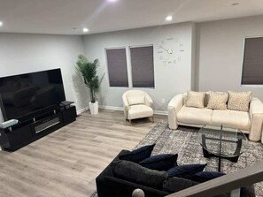 Una sala de estar moderna con una televisión de pantalla plana, un sofá, una silla y una mesa de centro.