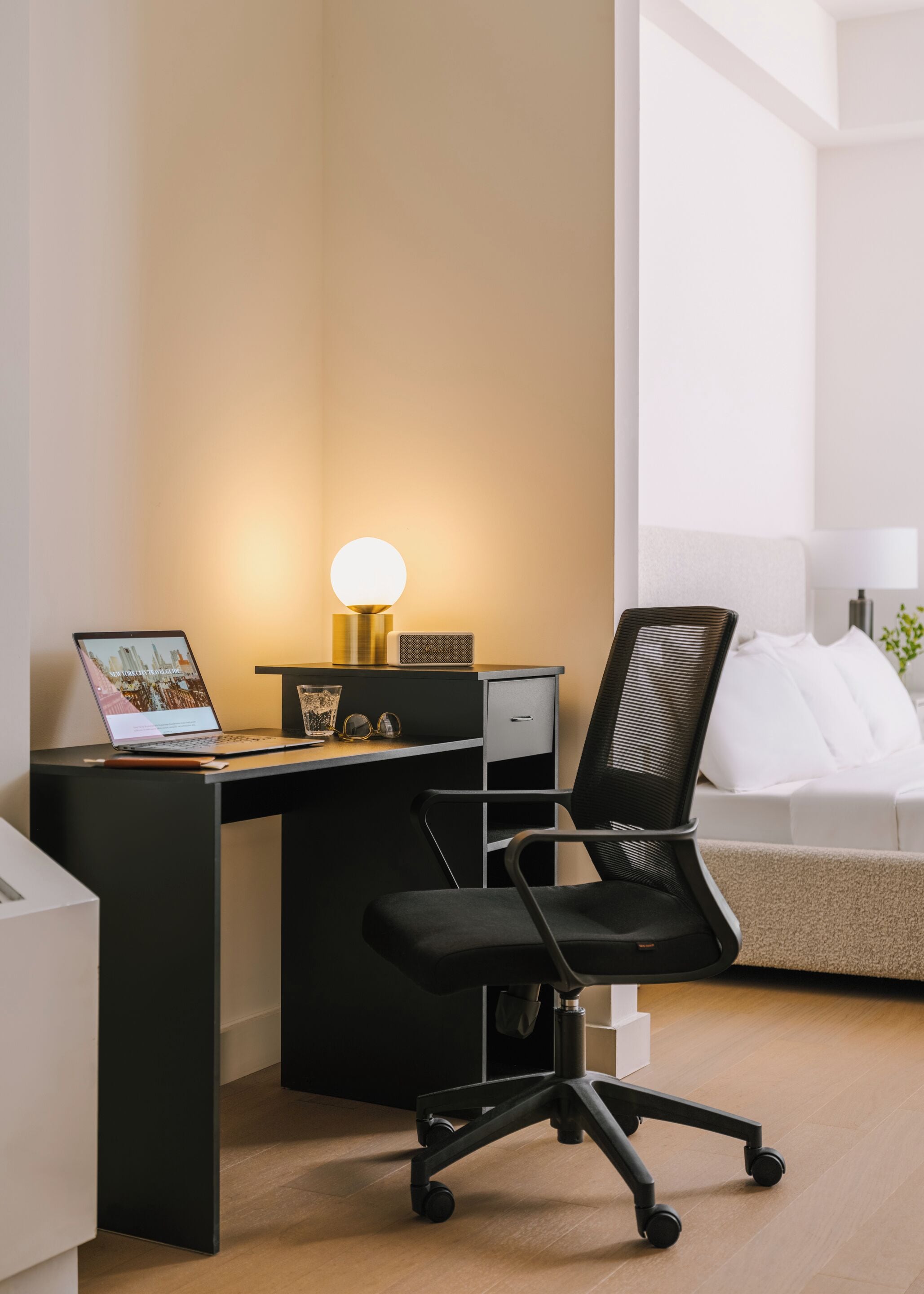 A modern office desk with a laptop, a lamp, and a chair.