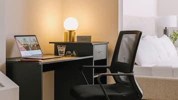A modern office desk with a laptop, a lamp, and a chair.
