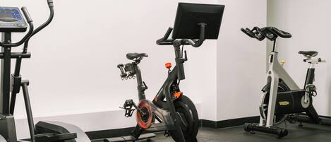 A gym with stationary bikes, a treadmill, and a rowing machine.
