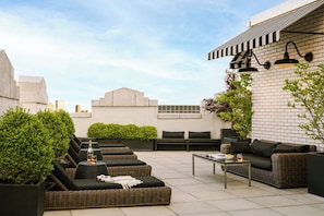 A rooftop patio with outdoor seating, a table, and a brick wall. - Nester Finn Financial District (New York)