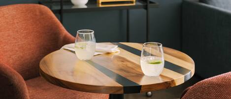 Un comedor con dos sillas, una mesa redonda y un espejo hexagonal en la pared.