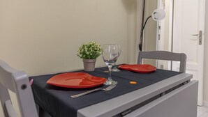 Uma mesa de jantar com um vaso de planta, uma taça de vinho e pratos vermelhos.