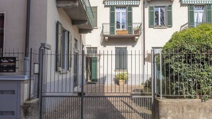 Um pátio murado com um edifício com varandas e portadas verdes.