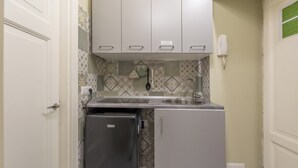 Uma cozinha compacta com geladeira, pia e azulejos decorativos na parede.