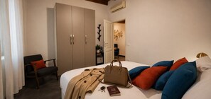 A bedroom with a bed, a chair, a wardrobe, and a handbag. - Red Door Dream Apt. 5 (Firenze)