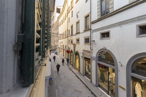 A narrow street with shops on either side, featuring arched windows and a pedestrian walkway. - Red Door Dream Apt. 5 (Firenze)