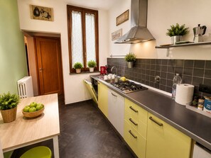 Cocina moderna con estufa a gas, pileta y ventana con cortinas.