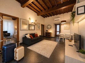 Ein modernes Wohnzimmer mit einer Couch, einem Essbereich mit Tisch und Stühlen, einem Fernseher und einem großen Fenster.