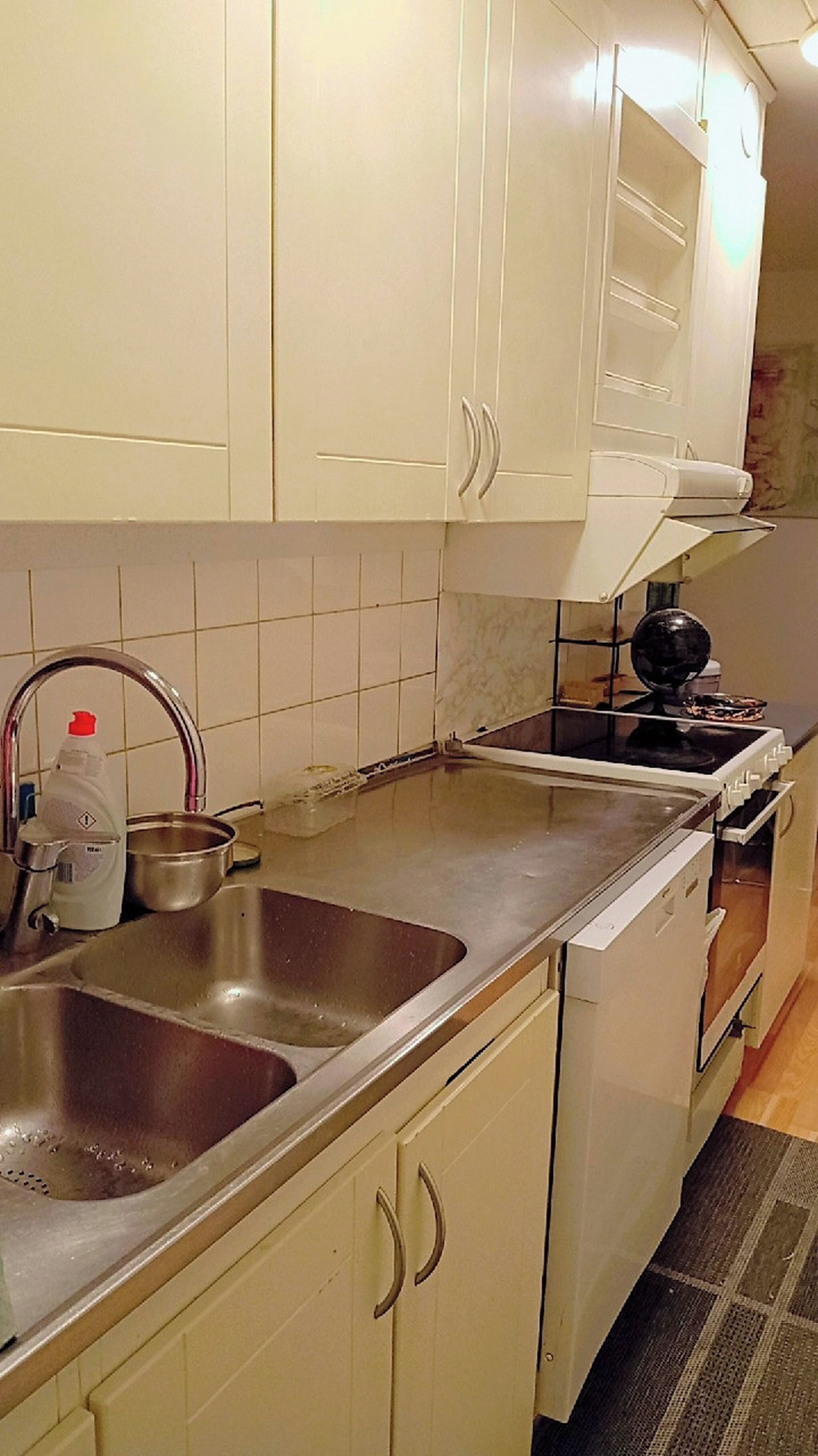 A kitchen with white cabinets, a stainless steel sink, a stove, and a microwave.