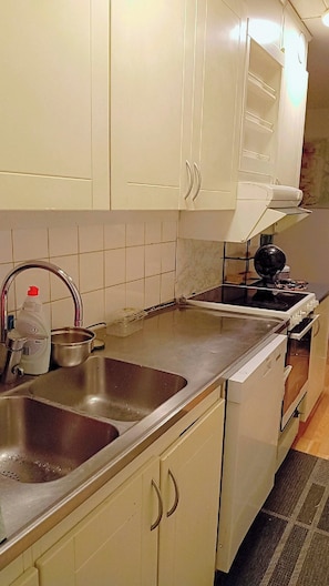 A kitchen with white cabinets, a stainless steel sink, a stove, and a microwave. - Room-charming Apartment With Private Ent (Uppsala)