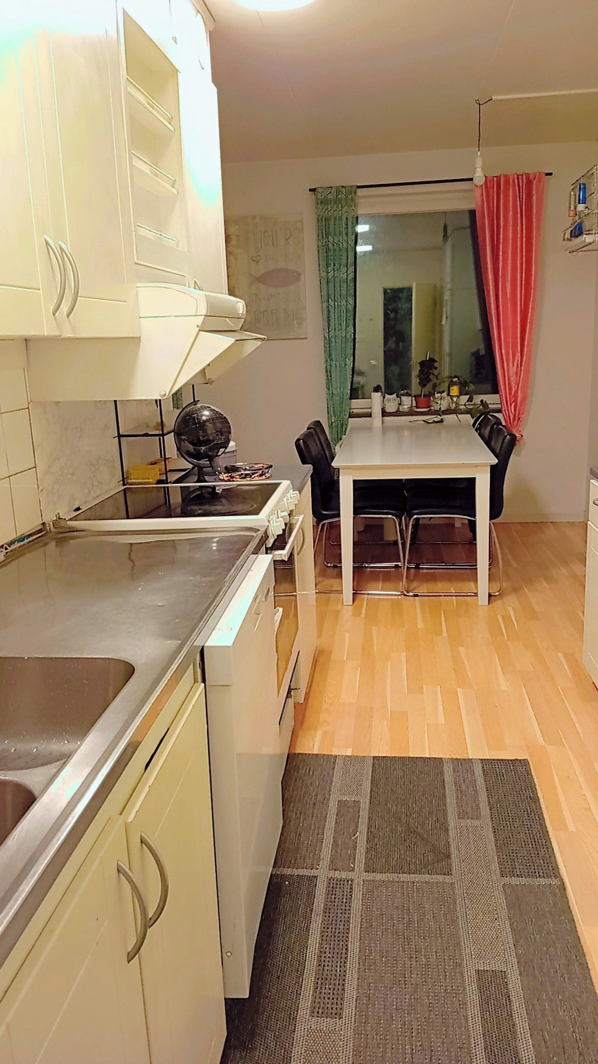 Una cocina compacta con comedor, refrigerador, estufa y pileta.