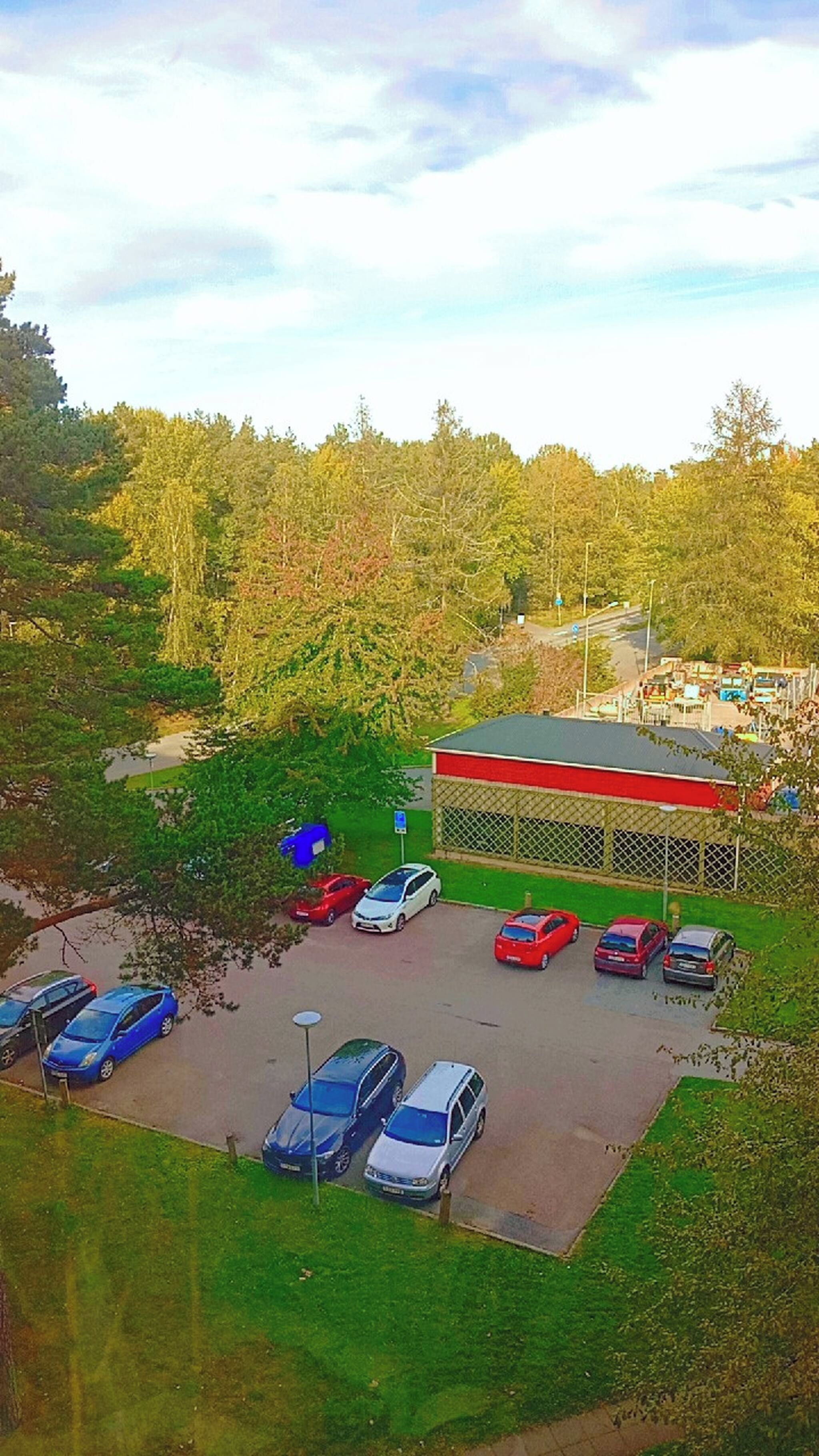 A parking lot with several cars and a building with a red roof.