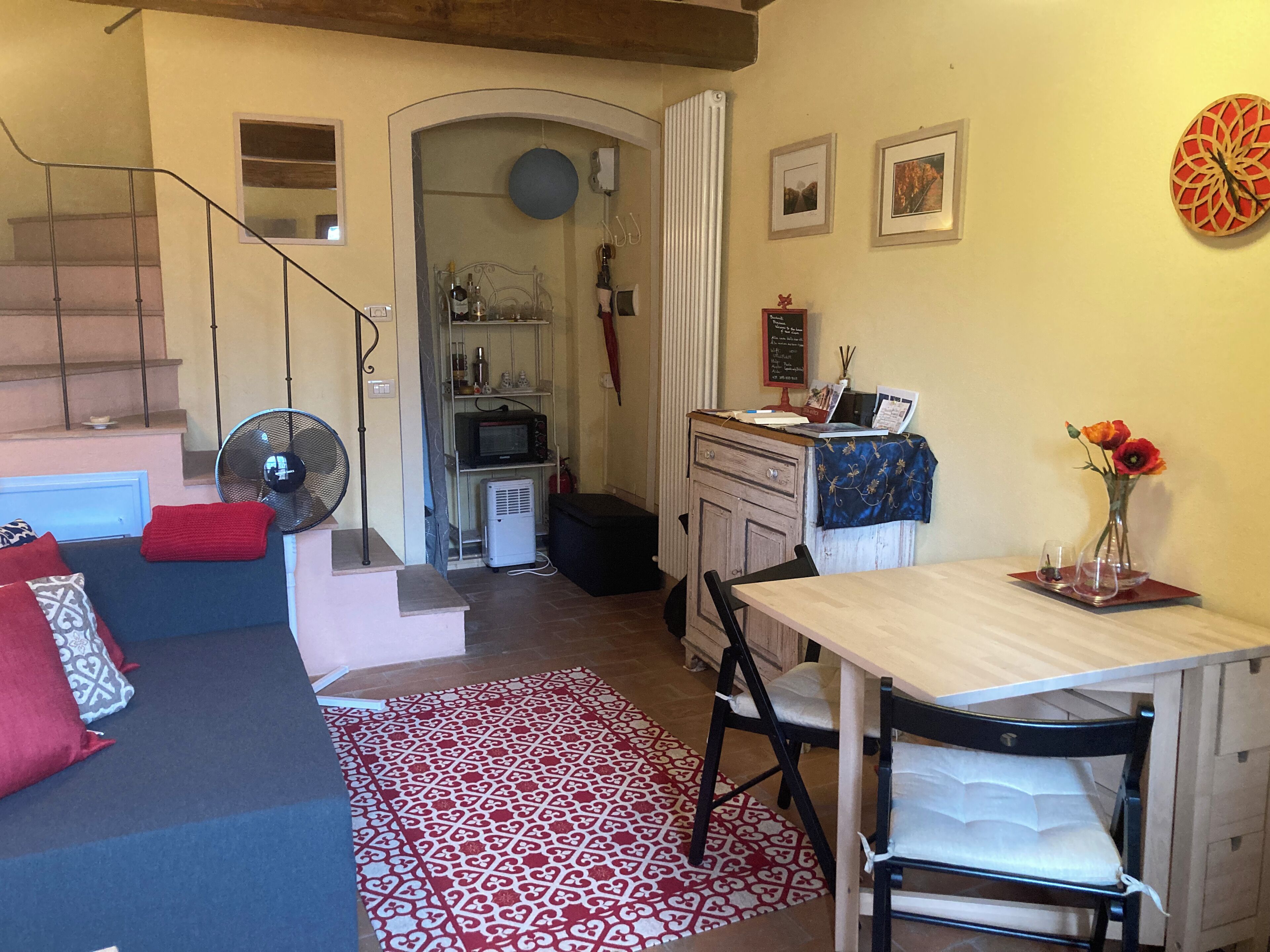 Een gezellige woonkamer met een bank, een eettafel en een keuken op de achtergrond.