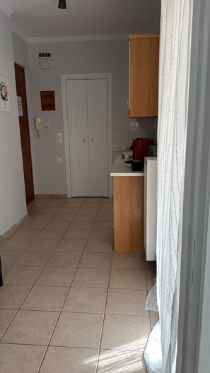 Eine Küche mit einem weißen Kühlschrank, Holzschränken und Fliesenboden.