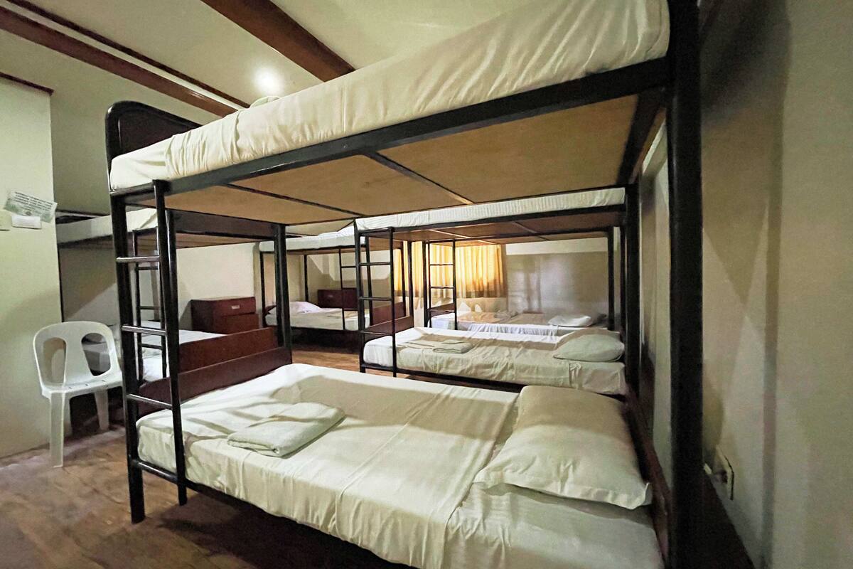 Un dormitorio con literas, una silla de plástico blanco y un escritorio de madera.
