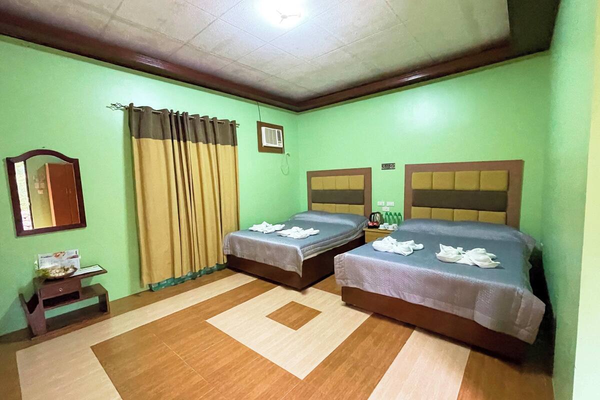 Una habitación con dos camas, un espejo, una mesita y una ventana con cortinas.