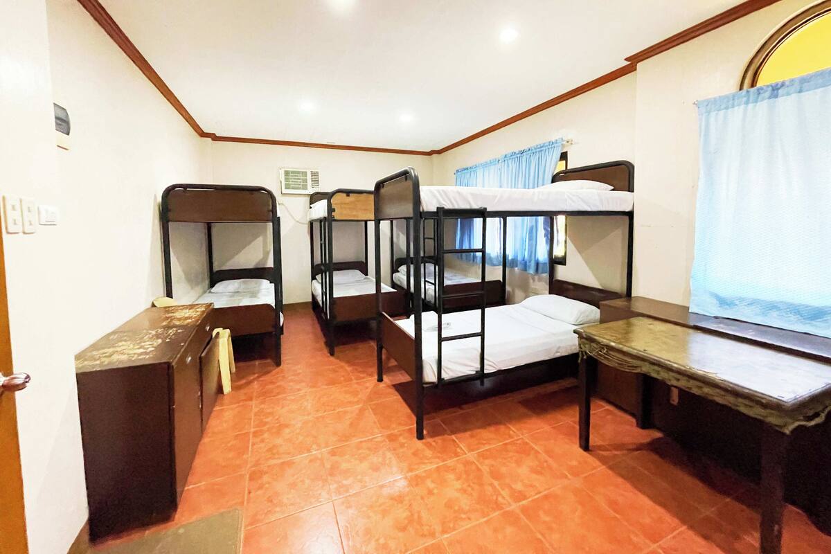 Una habitación con tres literas, una mesita y un armario.