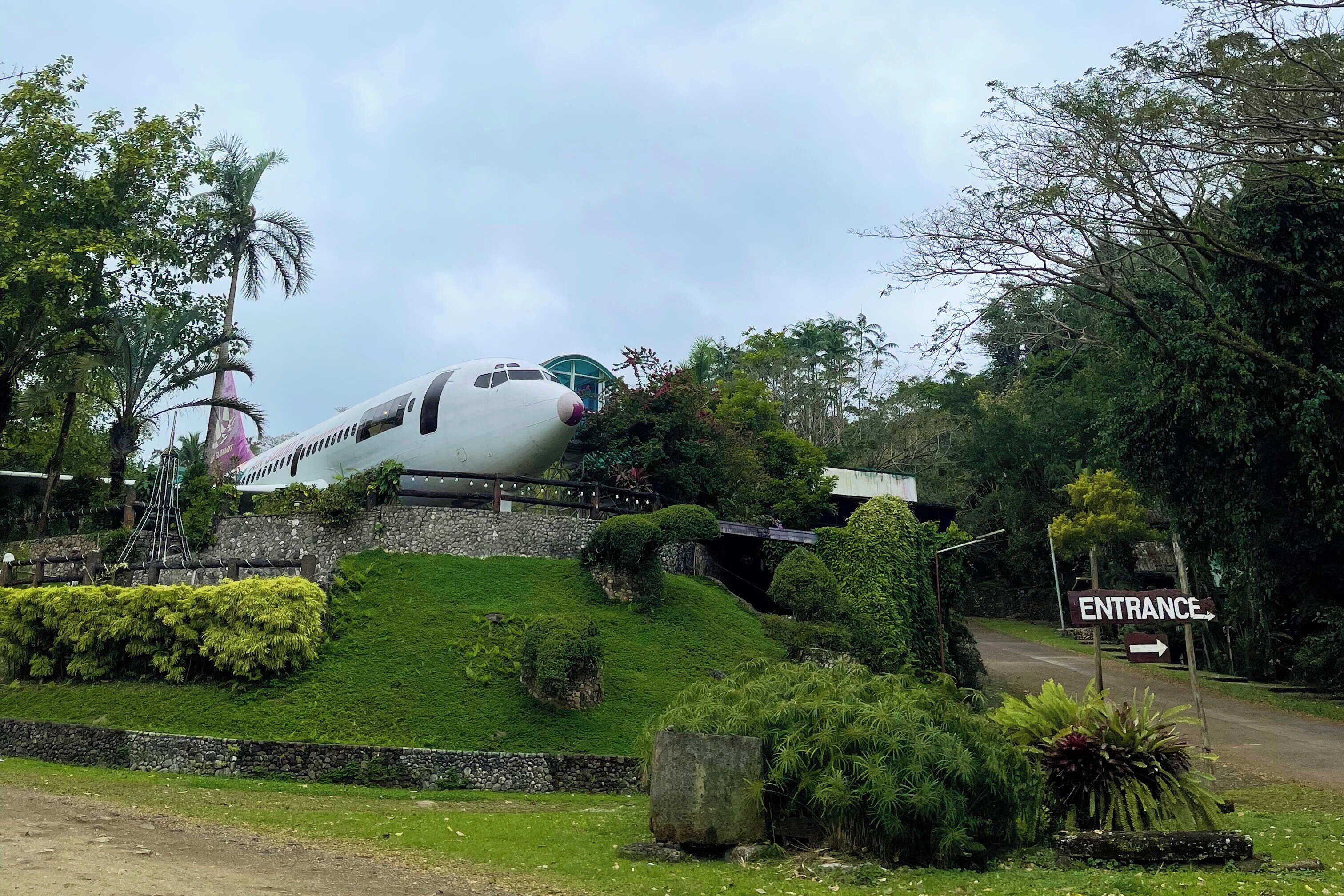 An airplane parked on a grassy area with a sign indicating an entrance.