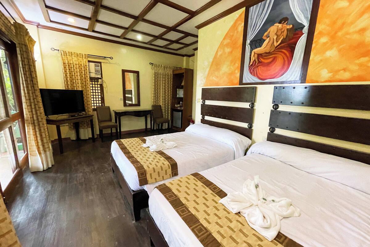 Habitación de hotel con dos camas, un televisor, un escritorio y un cuadro en la pared.
