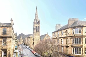 A street view with historic buildings, a prominent church tower, and parked cars along the road. - Stylish Southside Flat Near Old Town (Edinburgh)