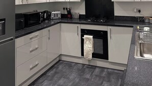 A modern kitchen with white cabinets, a black range hood, and a stainless steel sink. - Contractor/Corporate-Friendly Home | Sleeps 6 | Long Stays (Bolton)