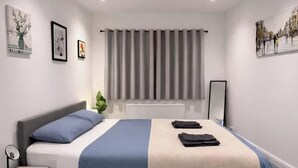 A modern bedroom with a bed, bedside tables, a mirror, and a window with curtains. - Contractor/Corporate-Friendly Home | Sleeps 6 | Long Stays (Bolton)
