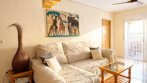 Un soggiorno con un divano, un tavolino, un vaso e un quadro appeso al muro.