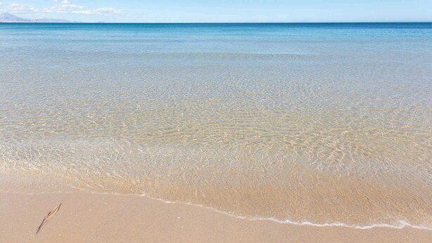Una spiaggia con acque cristalline basse e una riva sabbiosa.