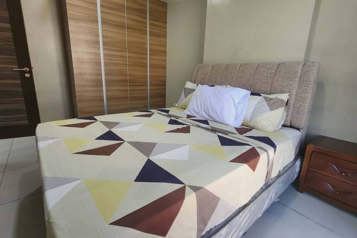 Une chambre à coucher avec un lit, une table de chevet et une armoire en bois.