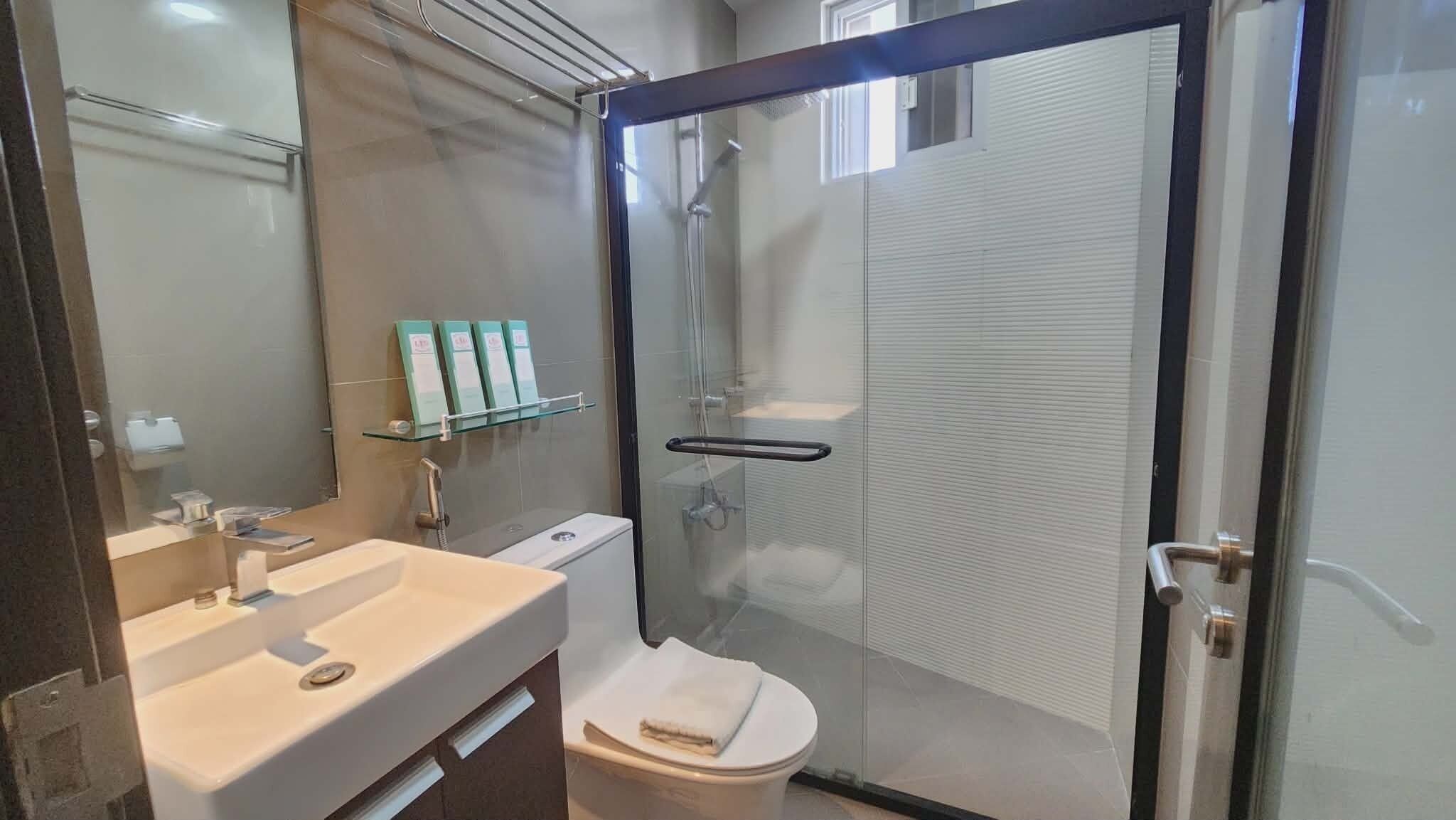 Une salle de bain moderne avec une douche à parois de verre, un lavabo blanc et des toilettes.