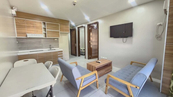 A compact living space with a kitchenette, a TV mounted on the wall, a sofa, and a small table. - LTG Grand Hotel Cebu (Cebu City)