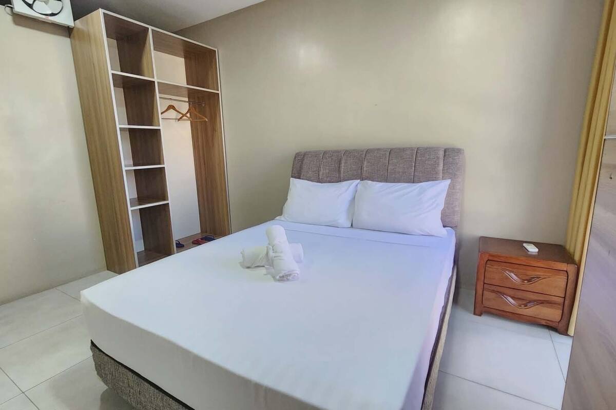 Une chambre à coucher avec un lit, une armoire en bois, une table de chevet et une serviette sur le lit.