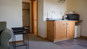 Una cucina funzionale con un pensile in legno, un lavello e un forno a microonde. In primo piano, un tavolino e una sedia.