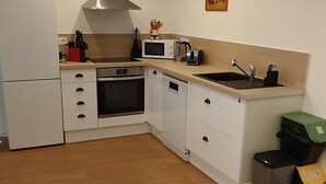 A modern kitchen with white cabinetry, a stainless steel range hood, a built-in oven, and a sink. - Apartment at Suzannala 5 minutes from Colmar 6 people (Ingersheim)