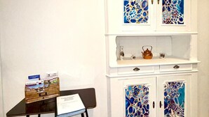 A room with a white cabinet featuring abstract stained glass doors, a small table with brochures, and a chair. - Apartment at Suzannala 5 minutes from Colmar 6 people (Ingersheim)