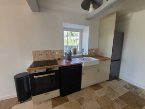A kitchen with a black dishwasher, a built-in oven, a sink, and a window above it. - Provencal house, wooded garden near Grignan 4-6 pers, 2 bedrooms (Réauville)