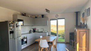 Une cuisine moderne avec un coin repas, un grand réfrigérateur et une vue sur l’extérieur.